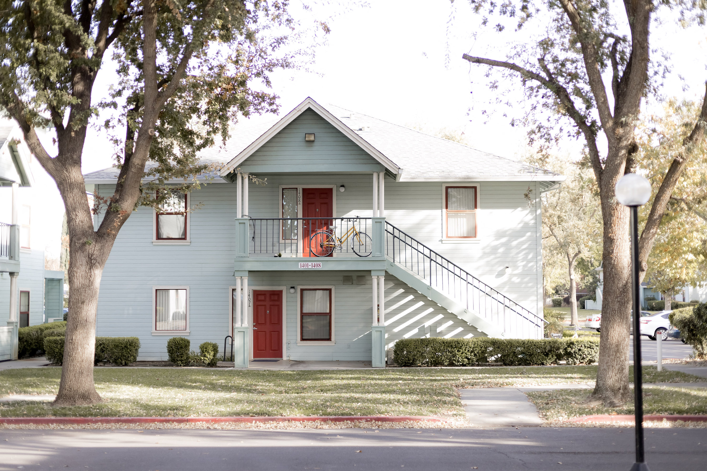 Teal two story building with red doors and stairwell to the right